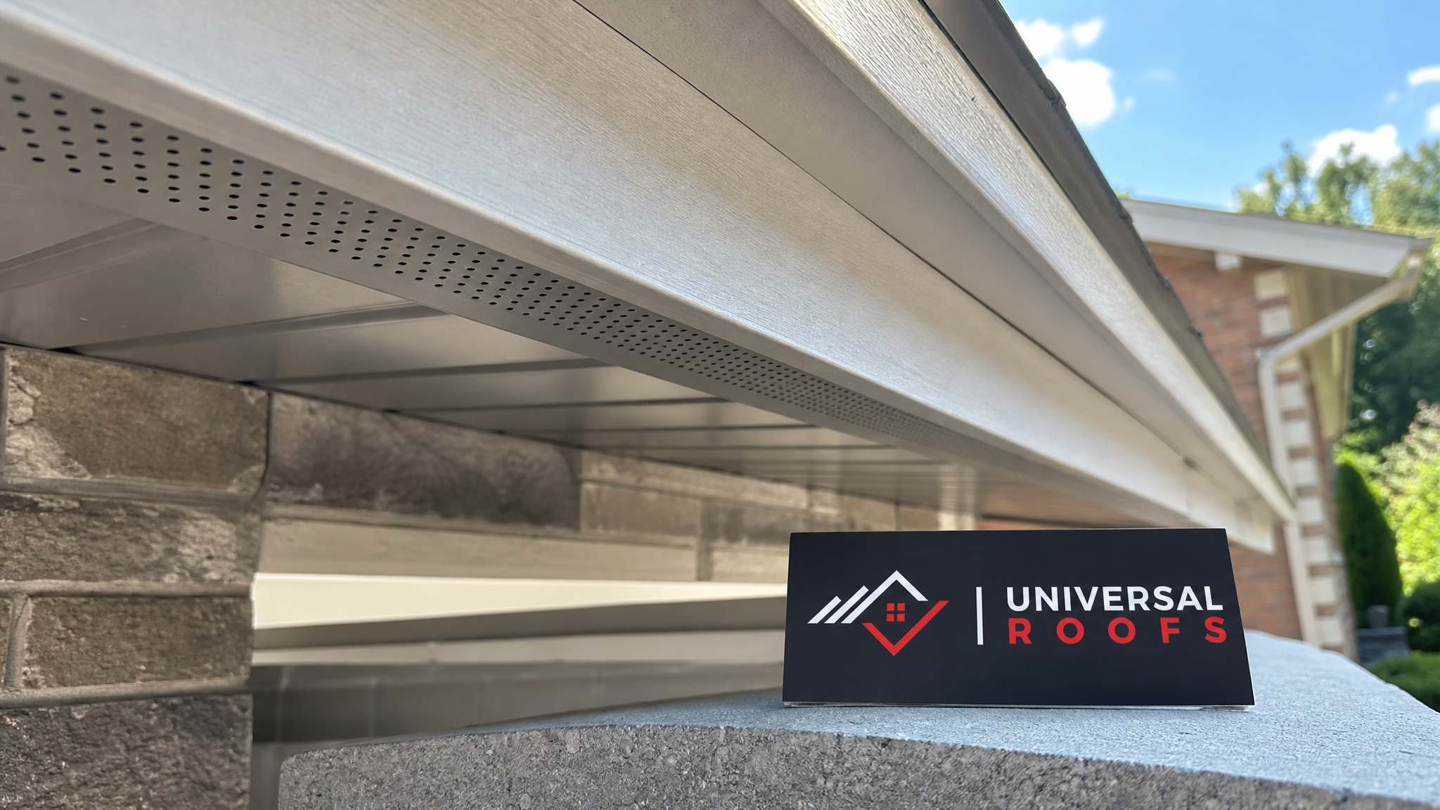 Close-up of a continuous soffit intake vent strip installed under a roof eave showing the perforated venting material