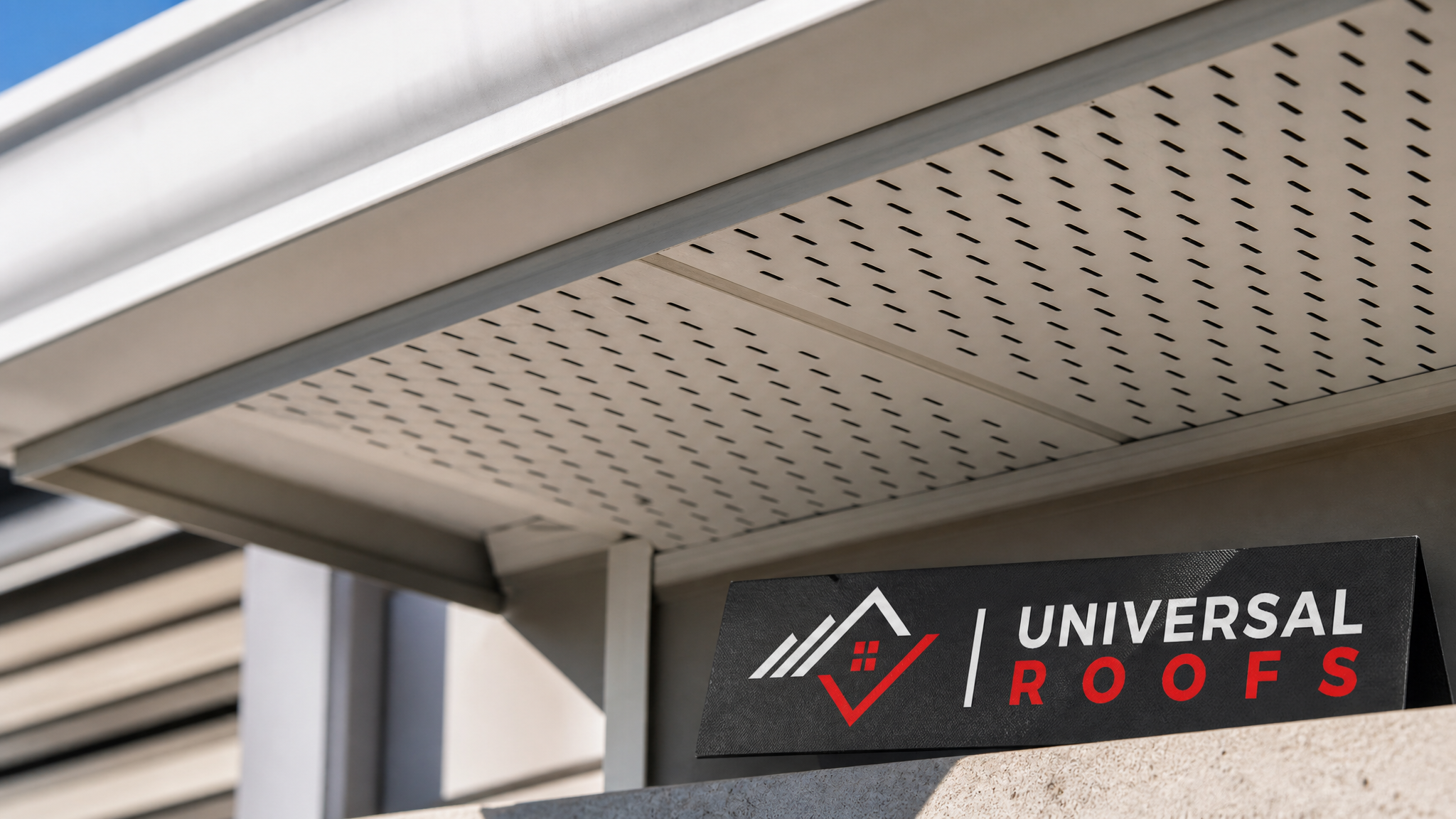 Close-up of a continuous soffit vent panel showing clear perforations for attic airflow with a Universal Roofs sign placard nearby
