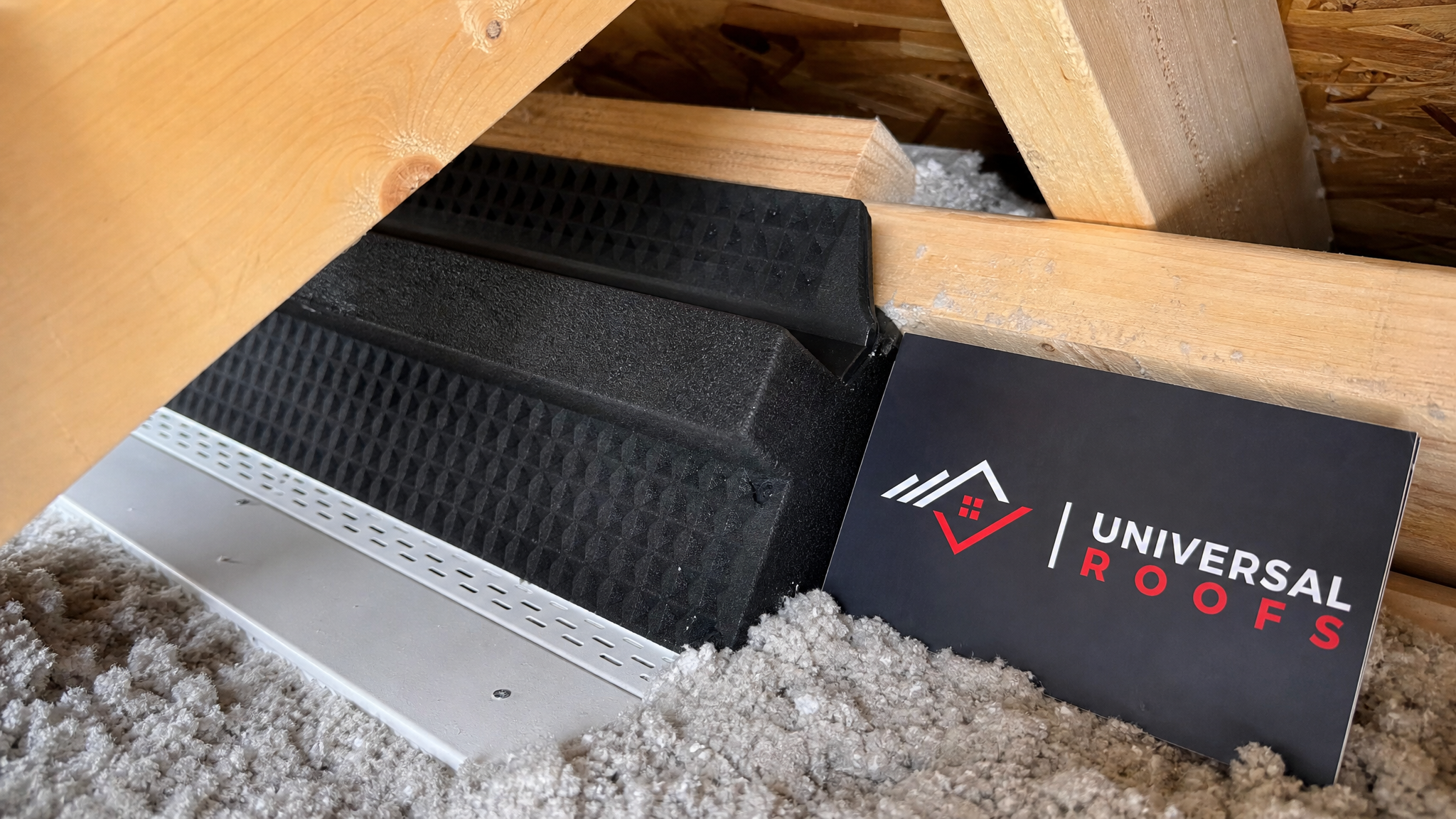 Close-up of an attic soffit baffle keeping ventilation airflow clear beneath new insulation