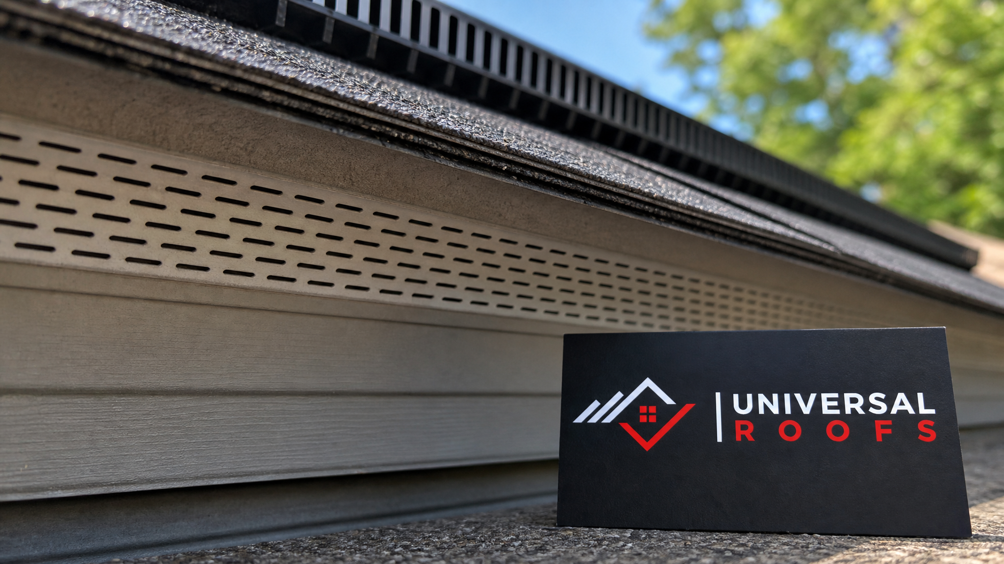 Close-up detail of a soffit intake vent and continuous ridge vent strip on a residential roof