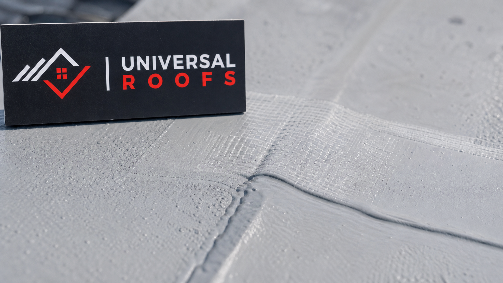 Close-up detail of a cured elastomeric roof coating seam reinforced with fabric mesh, showing smooth flexible finish
