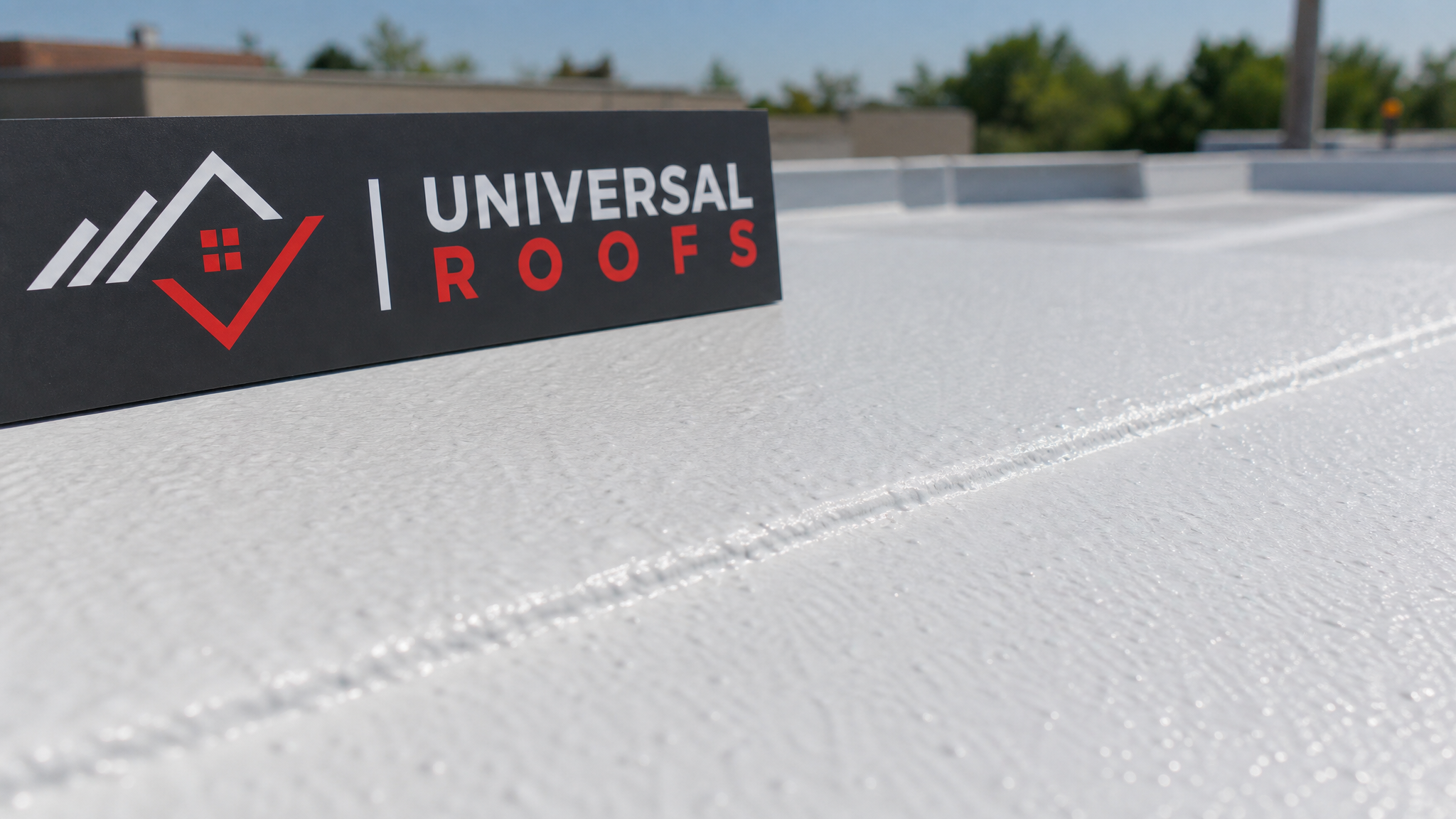 Close-up detail of a white reflective roof coating seam and texture on a flat roof membrane with a Universal Roofs branded sign placard nearby