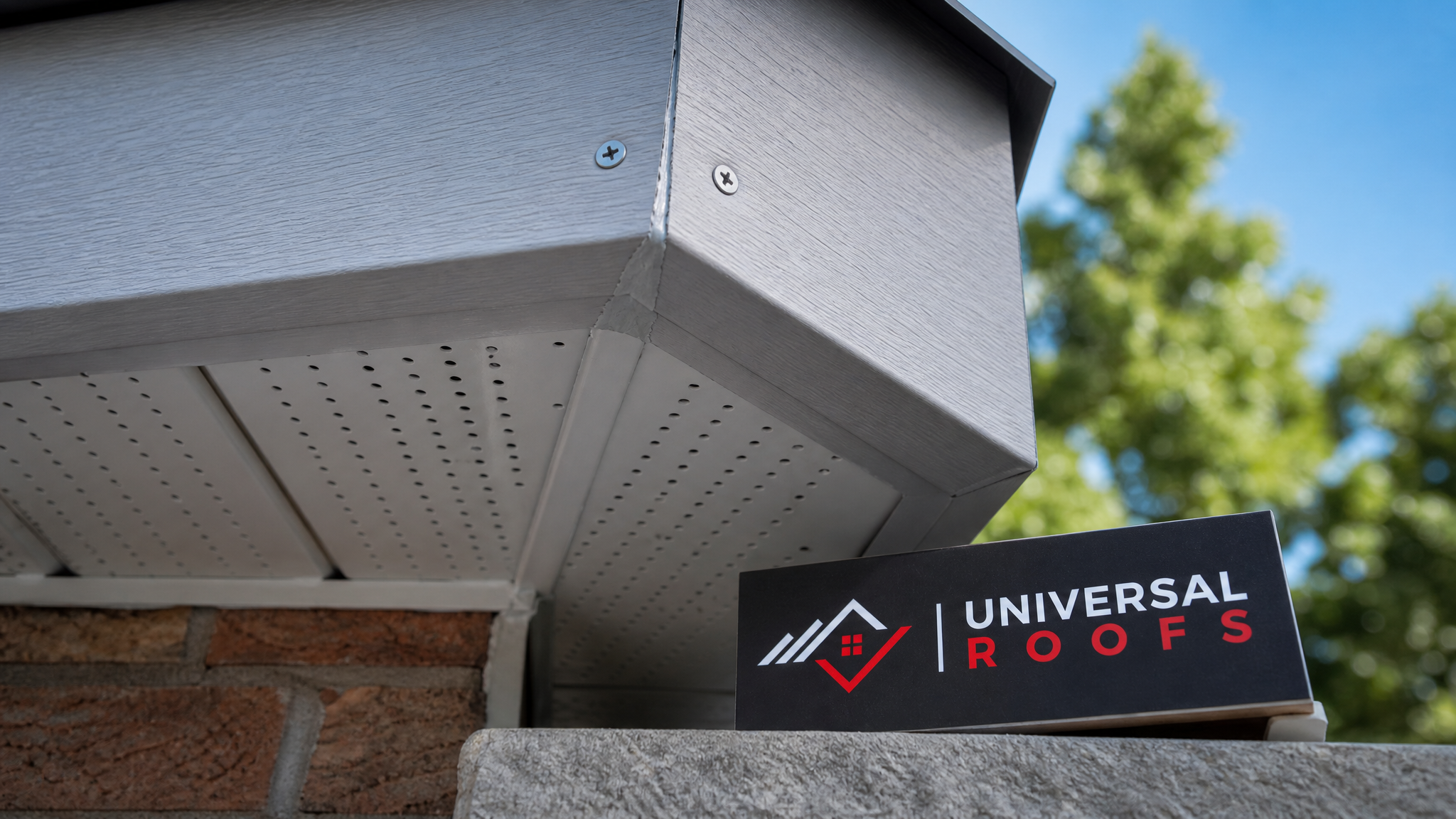 Close-up detail of perforated aluminum soffit panel and fascia joint showing clean fastening and sealed seams