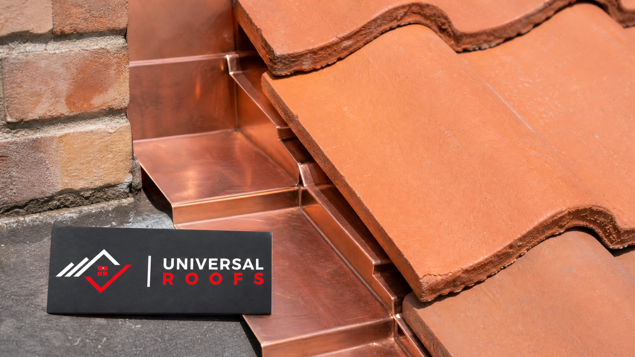 Close-up of new copper step flashing interlocking with clay roof tiles