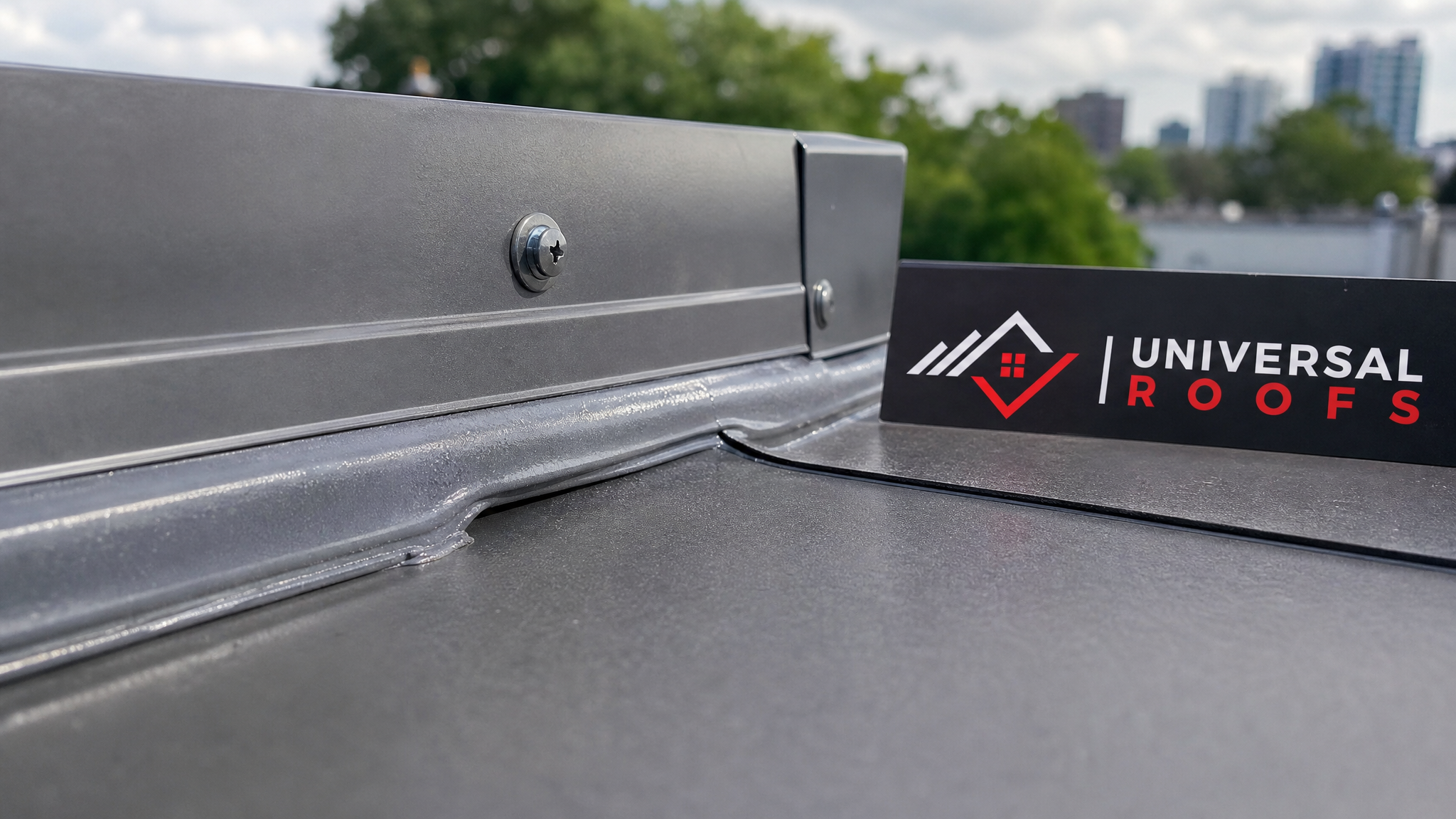 Close-up of overlapping metal flat roof flashing seams with sealant bead and termination bar detail