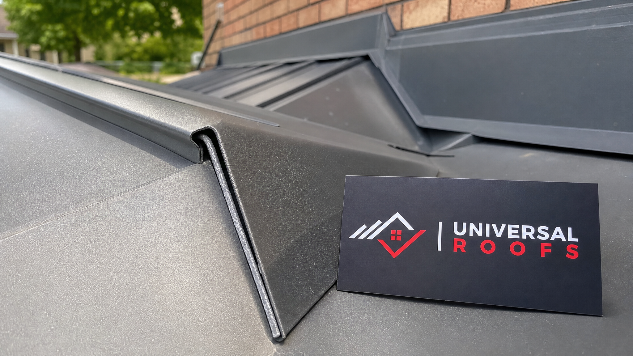 Close-up of a sealed standing seam metal roof joint with butyl tape and flashing detail, branded sign placard nearby